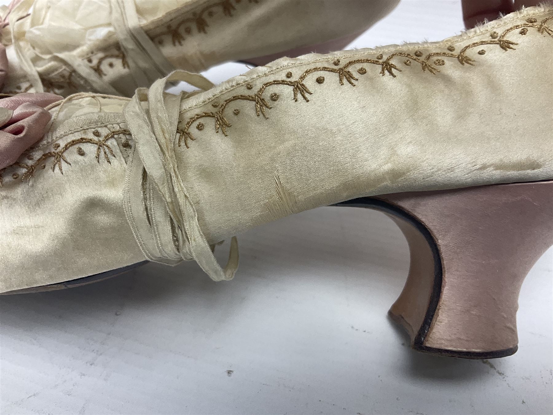 Pair of 19th century ivory silk satin ladies shoes, with rosette to the vamp, with pink silk satin heel, L23cm