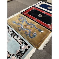 Collection of four Chinese washed woollen rugs - blue ground (153cm x 92cm); red and black ground (156cm x 94cm); light blue ground (138cm x 70cm); gold ground (153cm x 77cm)