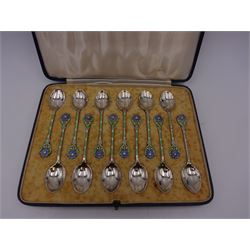 Set of twelve silver coffee spoons, each with enamelled blue flower to terminal and green and white enamel decoration to stem, hallmarked Mappin & Webb Ltd, Birmingham 1934, contained within fitted case