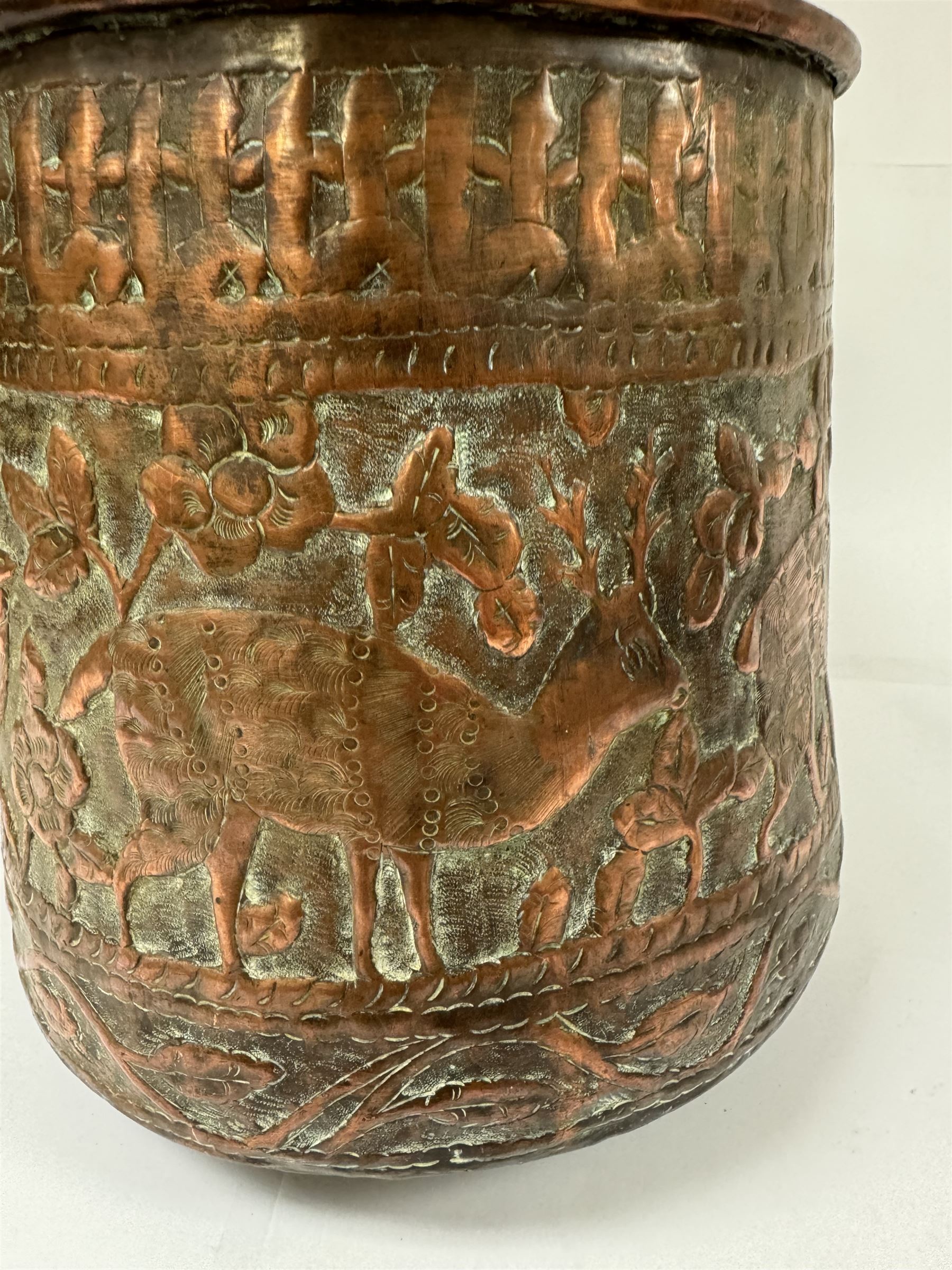 Middle eastern copper bucket, with chased and embossed band of animal decoration, together with a copper jardinière embossed with floral panels, copper plate with embossed leaf motif and two brass helmet shaped coal scuttles, bucket H26cm