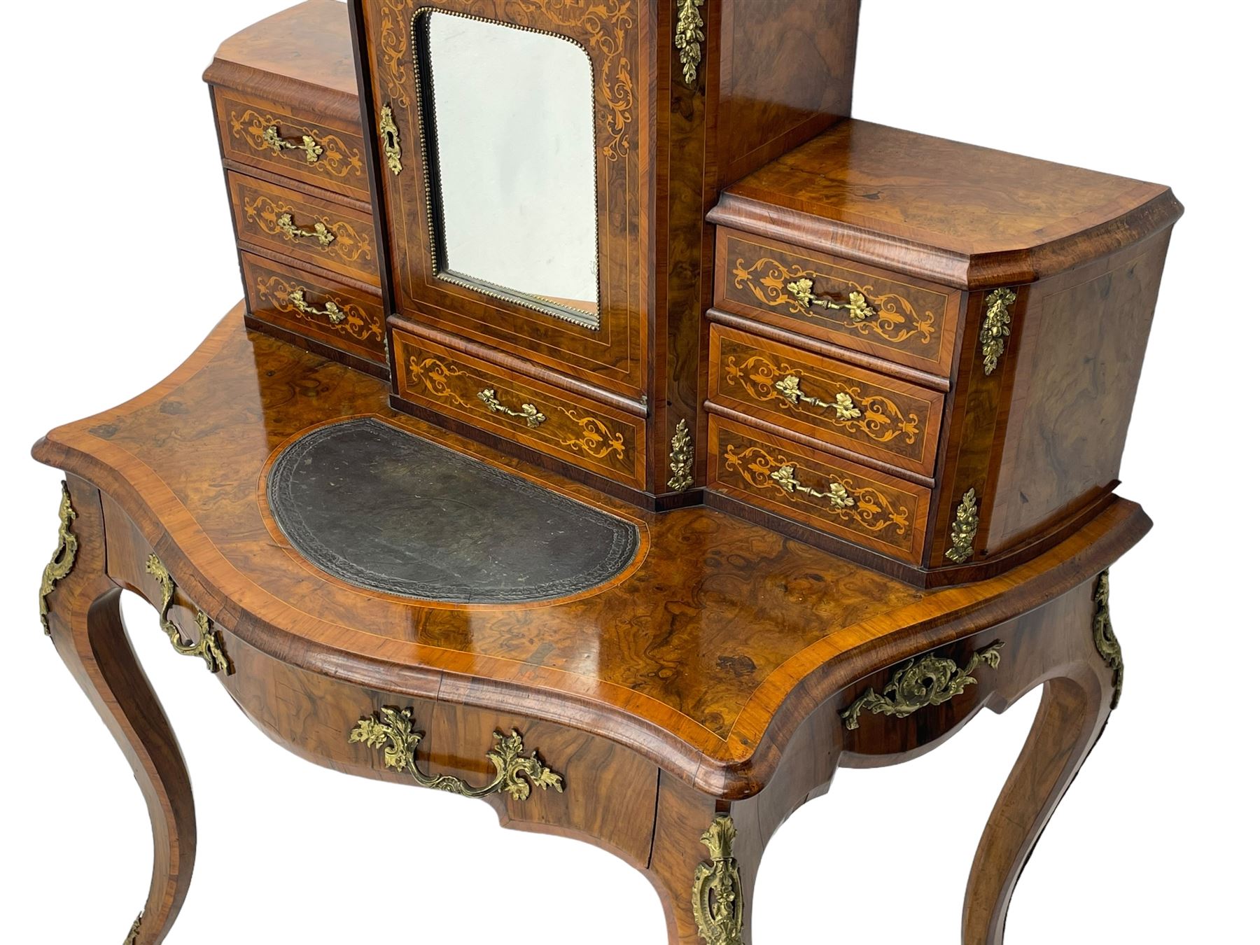 19th century French figured walnut Bonheur de Jour or writing desk, the upper section with brass gallery over mirror glazed cupboard and a combination of drawers, shaped and moulded top with leather inset and satinwood band, fitted with single drawer, on cabriole supports, inlaid throughout with scrolling foliate decoration in boxwood, ornate cast brass mounts 