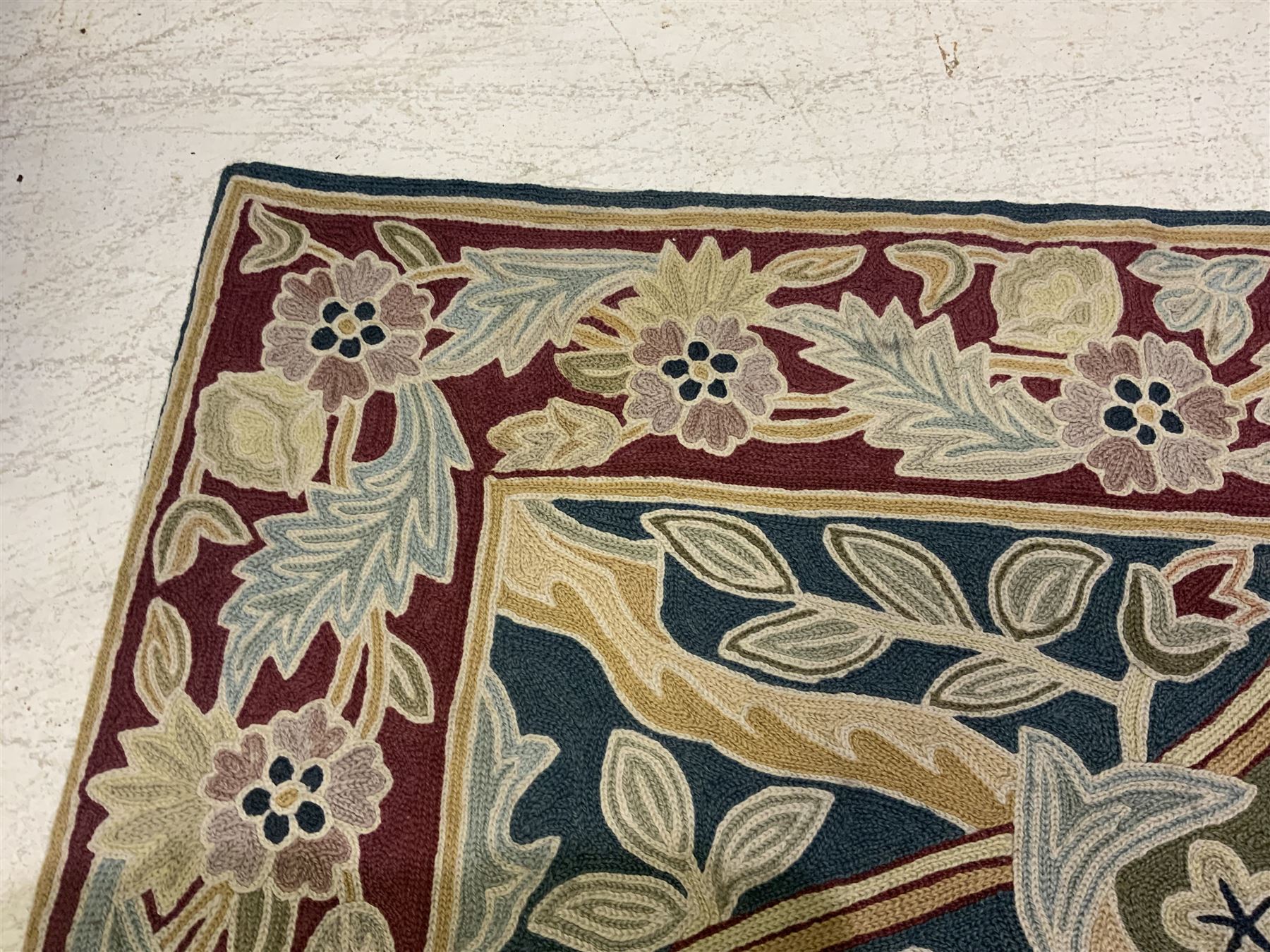 Caucasian design crewelwork hanging, the field decorated with a stylised tree of life motifs with surrounding leafage, enclosed by a crimson ground border with foliate designs