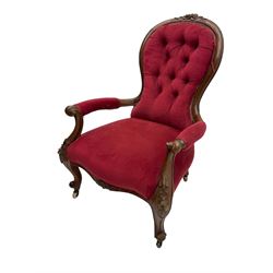 Victorian walnut open armchair, the cresting rail carved with flower heads and extending foliage, upholstered in buttoned red leather, scrolled arms and cabriole supports carved with flowers