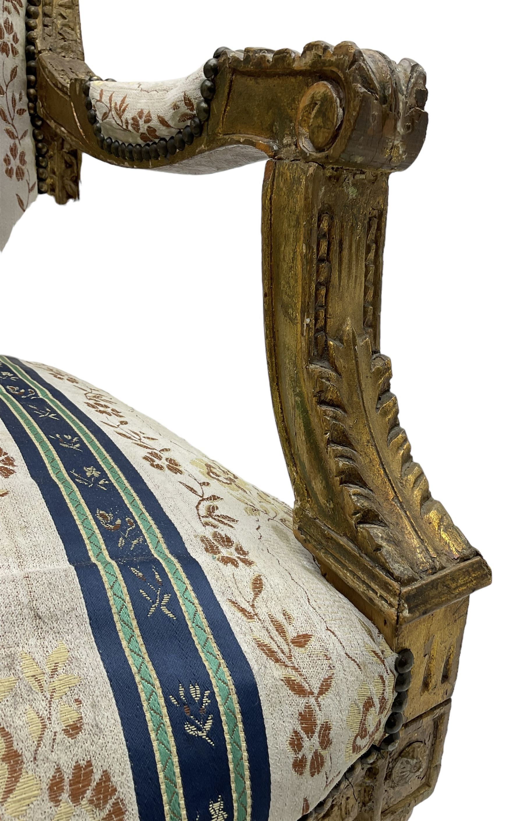 Late 20th century French design carved giltwood armchair, the cresting rail carved with scrolled foliage over foliate carved platform, upholstered in striped fabric decorated with trailing foliage and flower heads, acanthus carved arm terminals and upright supports, on turned and fluted supports 