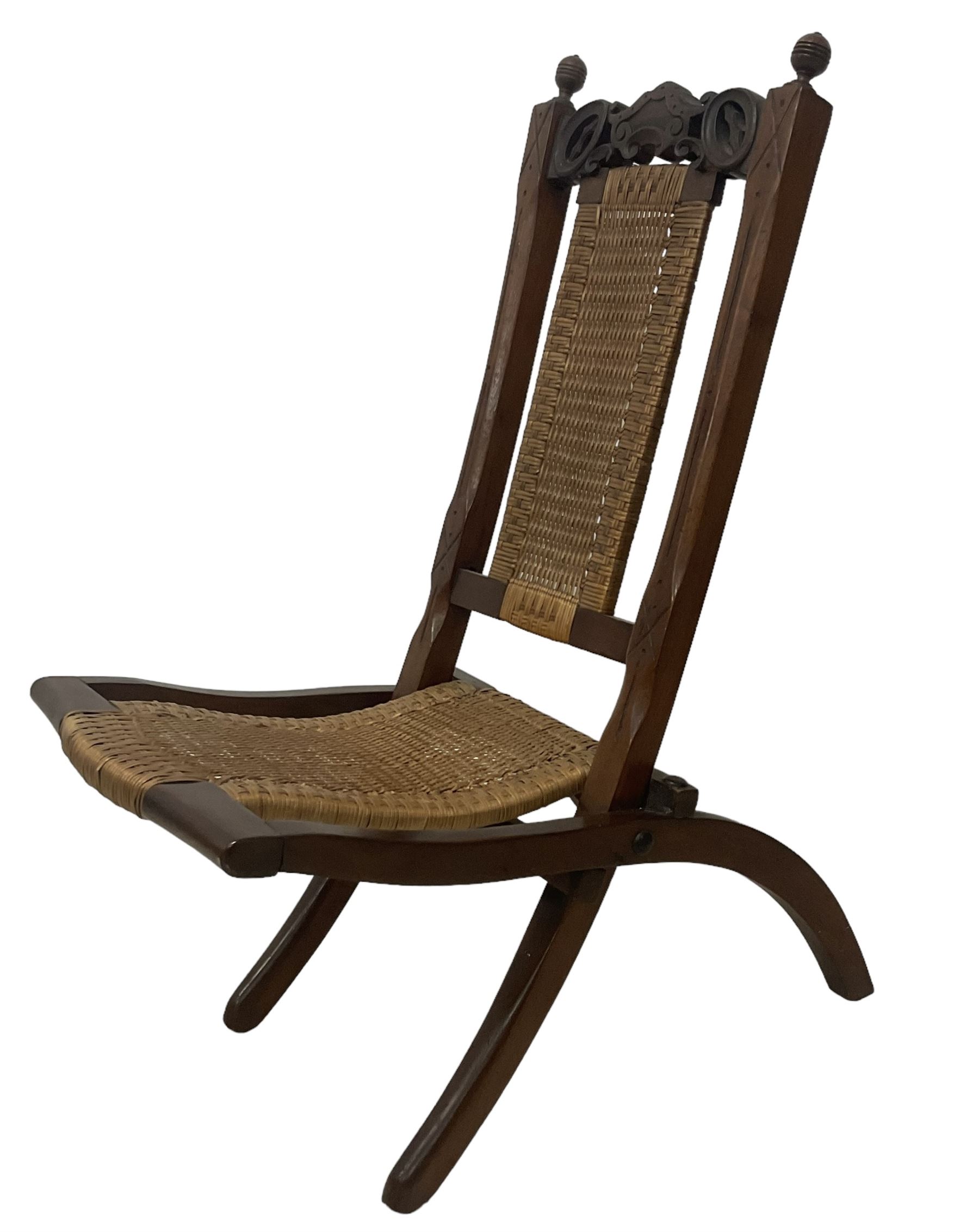 Victorian Aesthetic Movement mahogany framed folding campaign chair, pierced and carved cresting rail with carved and chamfered uprights, rattan back and seat