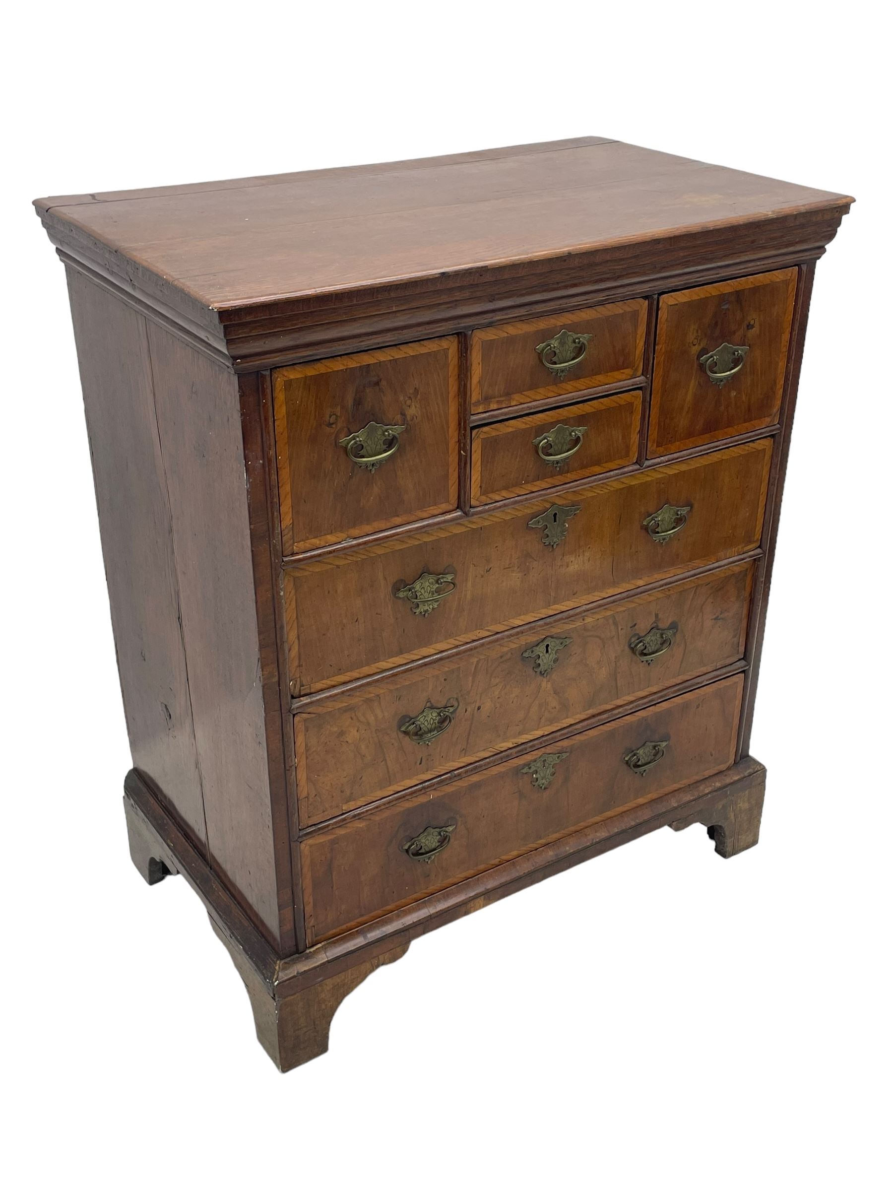 18th century oak and walnut chest, fitted with four small over three long drawers with figured walnut facias, brass handles and plates with engraved decoration, on bracket feet