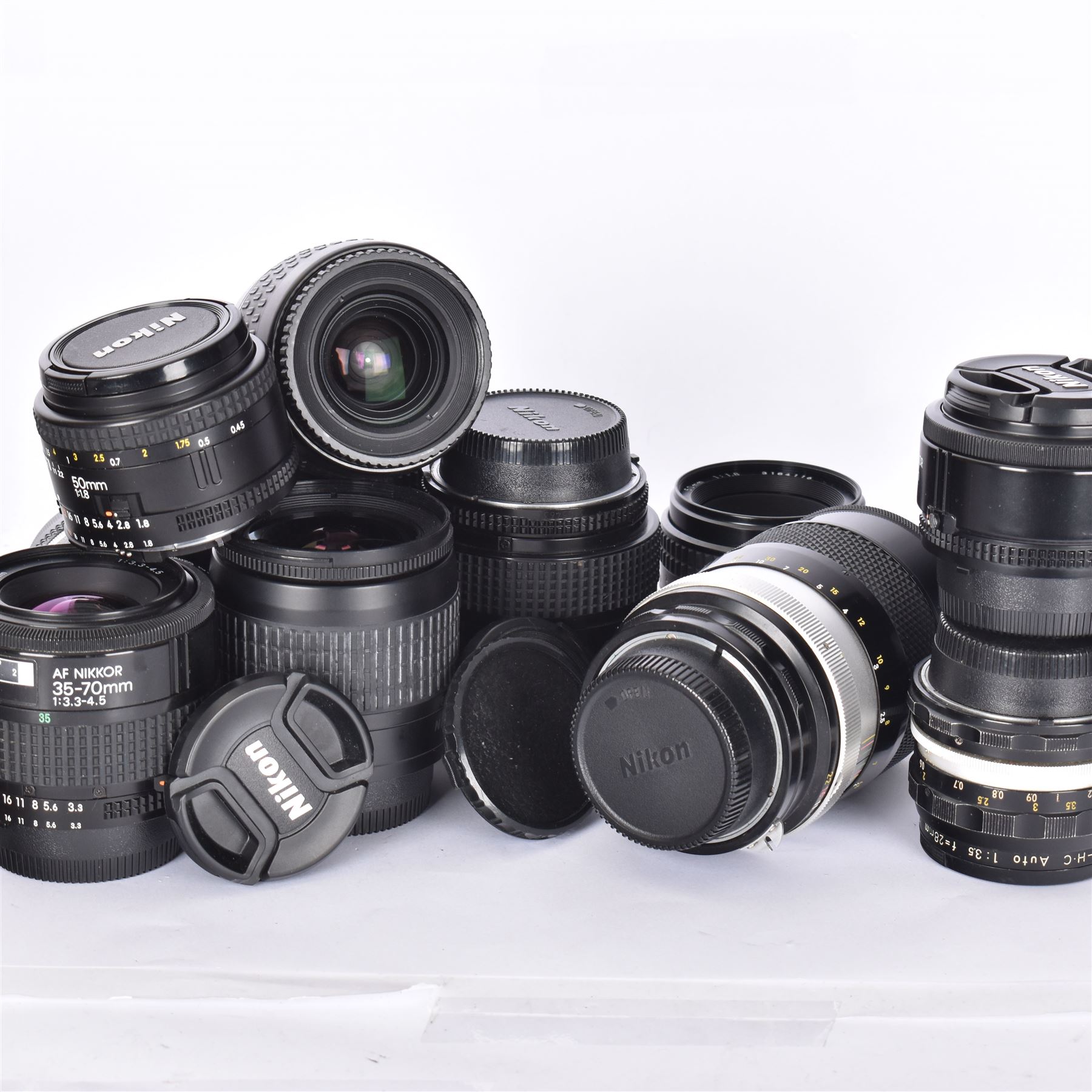 Eleven Nikon camera lenses, including AF Nikkor 35-70mm 1:3.5-4.5, nikkor-Q Auto 1:2.8 f=135mm and a Nikkor-HC Auto 1:3.5 f=28mm 