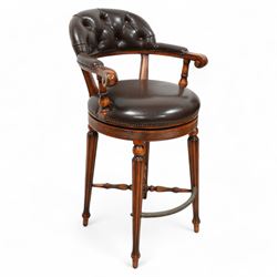 Pair of hardwood-framed bar stools, revolving tub seat with buttoned back rest and upholstered seat in brown leather, reed moulded seat rail over four lobe carved tapering supports, united by metal foot rest and x-framed stretchers 