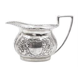 Edwardian silver milk jug, of helmet form with angular handle and oblique gadrooned ring, embossed with floral decoration and blank shield shaped cartouche, H8cm