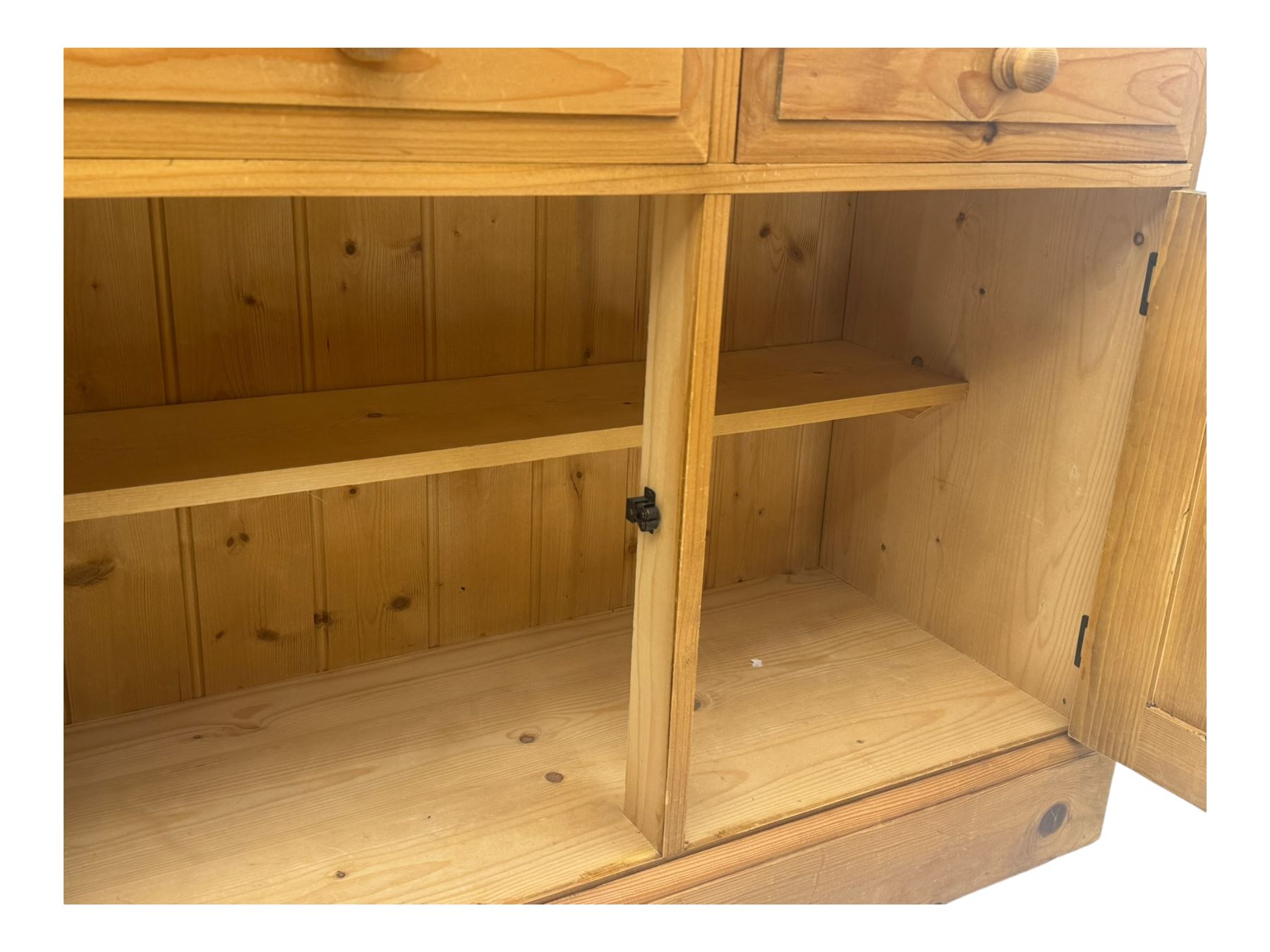 Large traditional pine dresser, shaped cornice over three open shelves, base fitted with four drawers above four panelled cupboards, each with turned wooden knobs, on plinth base