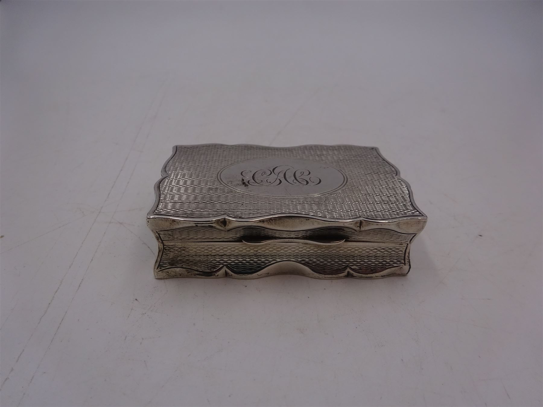 Edwardian silver snuff box, of rectangular form, with shaped edges, engine turned decoration throughout and engraved cartouche to hinged cover, opening to reveal a gilt interior, hallmarked Henry Charles Freeman, Birmingham 1904, W6cm