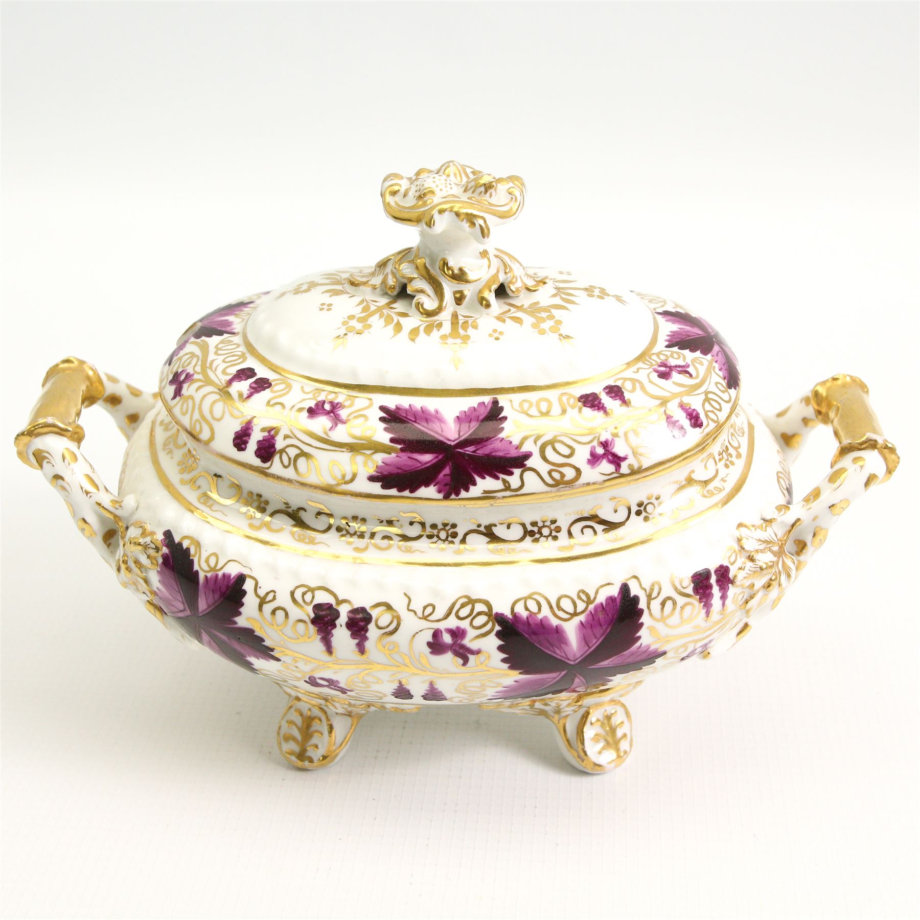 Pair of early 19th century porcelain sauce tureens and covers on stands, possibly Coalport, painted with bands of purple and gilt fruiting vines, within gadroon borders, the stands with naturalistic oak leaf and entwined moulded  handles, the covers with flower knop handles, stand L24cm, overall H18cm