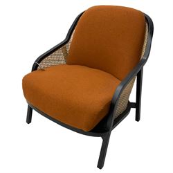 Contemporary MADE Anakie armchair, black lacquered frame with cane backrest, orange fabric upholstered seat and back cushion, sloped armrests, on splayed supports