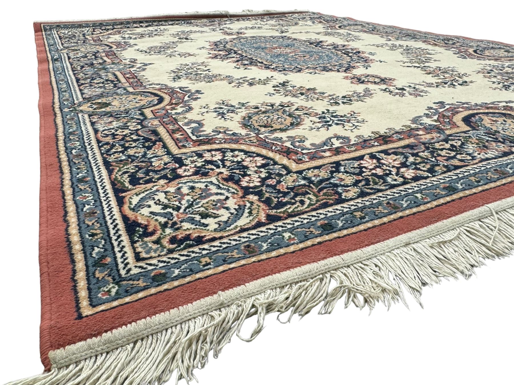 Persian design ivory ground rug, the field decorated with an oval medallion filled with floral motifs and scrolling vines, flanked by floral sprays and corner spandrels with palmette designs, the main border featuring a series of stylised floral patterns against a dark blue ground, enclosed by multiple guard stripes with geometric and floral motifs