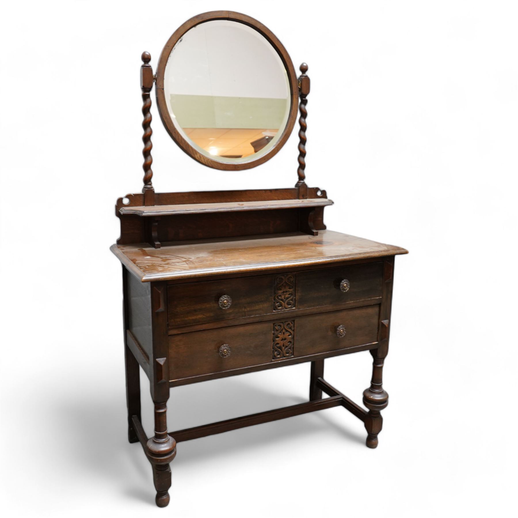 Art Nouveau oak dressing table, raised circular bevelled mirror on spiral turned supports, fitted with two drawers with scrolling foliate carvings, on turned supports joined by stretchers