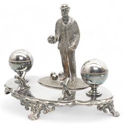 Victorian silver-plated inkstand by James Dixon & Sons, the quatrefoil base surmounted with a figure of a lawn bowler stood upon an oval grass base, with three lawn bowls by his feet, the inkwells formed as two bowls, each with hinged covers and silver-plated liners, bamboo moulded pen rest and gallery, supported by four pierced and splayed feet, L22cm x H17cm