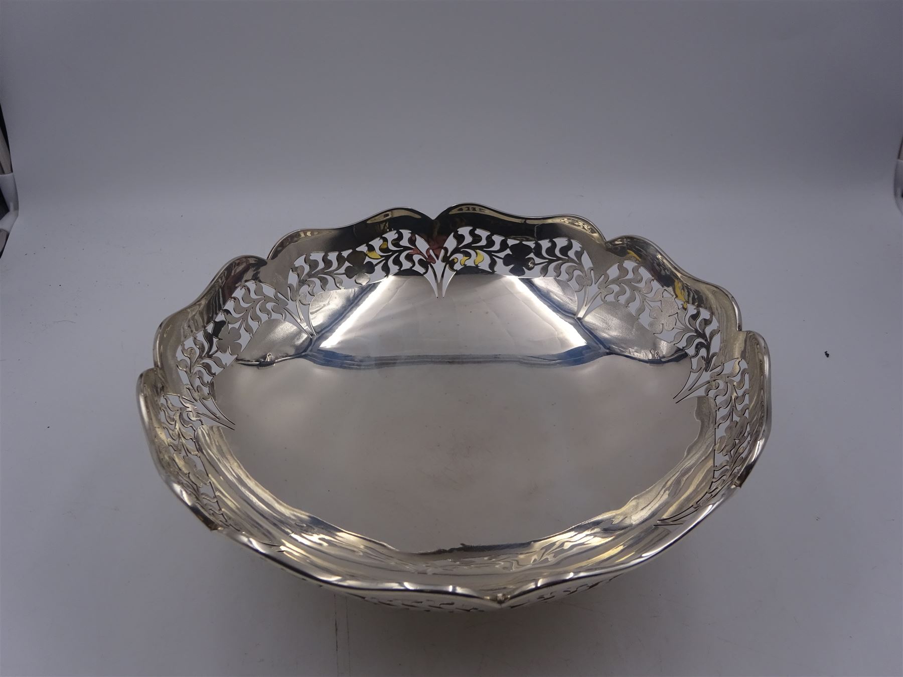 1920s silver bowl, of circular form with shaped rim, the sides with pierced foliate and floral decoration, upon four splayed feet, hallmarked Reid & Sons, London 1927, H9cm, D23cm