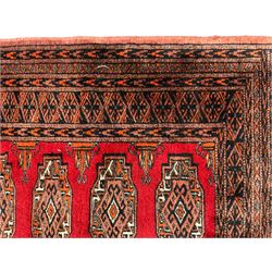 Persian Bokhara dark amber round rug, crimson field with six Gul motifs, surrounded by a guarded border with geometric design (124cm x 70cm); together with another similar in amber and red (101cm x 63cm) (2)