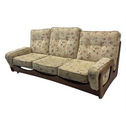 Mid-20th century three-seat sofa with floral patterned upholstery, supported by a sculpted teakwood frame with curved cutout detailing, loose cushioned back and seat, on tubular metal feet