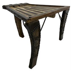 19th century Indian bullock / ox cart converted coffee table, trapezoidal top with applied metal decoration and iron stretchers, raised on three swept supports with stud decoration