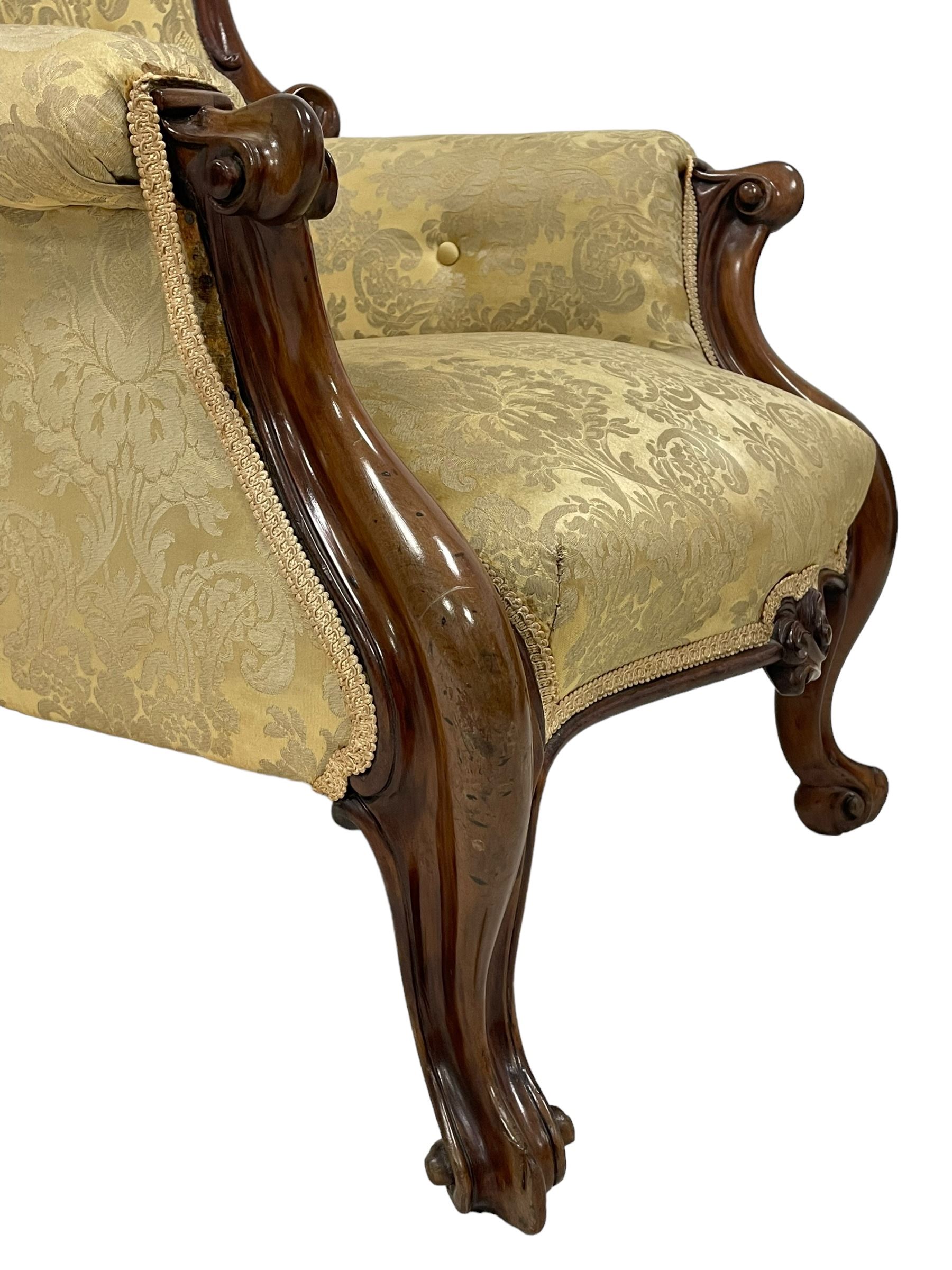 Victorian mahogany framed armchair, shaped and moulded frame carved with curled foliage, upholstered in pale gold floral pattern silk damask fabric, scrolled arm terminals on shaped moulded supports terminating to scroll carved feet