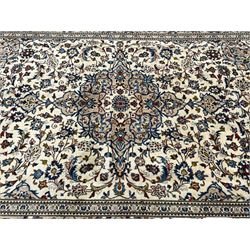 Persian Kashan ivory ground rug, central floral medallion surrounded by interlacing leafy branches and stylised plant motifs, scrolling spandrels, the border decorated with trailing branch and repeating palmettes, within floral pattern guard stripes 