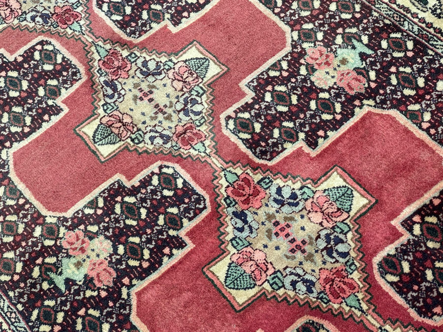 Kurdish rose ground runner rug, set with a series of ten floral medallions on linked field, the border decorated with stylised flower heads and bird motifs 