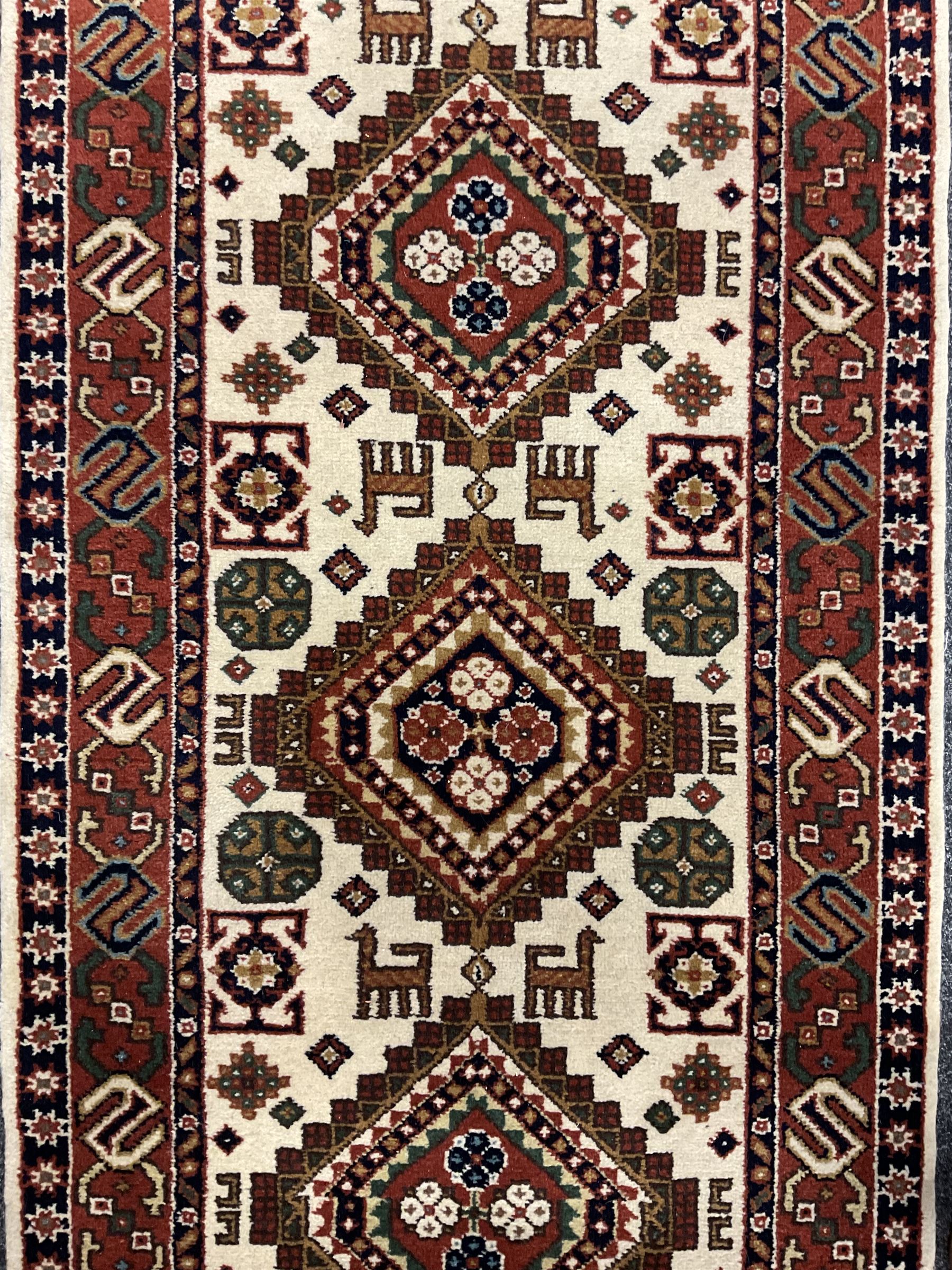 Persian design ivory ground rug, six lozenge medallions within a field of stylised animal and geometric motifs, the guarded border decorated with interconnected S motifs 