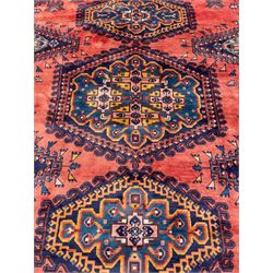 Persian Wiss pale crimson ground rug, three medallions with hooked borders, the field punctured with projecting lozenges, decorated with hac motifs, plain field decorated with stylised bird motifs, the border decorated with rosettes and repeating geometric motifs, within guard stripes 