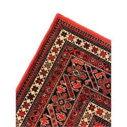 Persian design red ground rug, the field decorated with geometric motifs, repeating multiple band border 