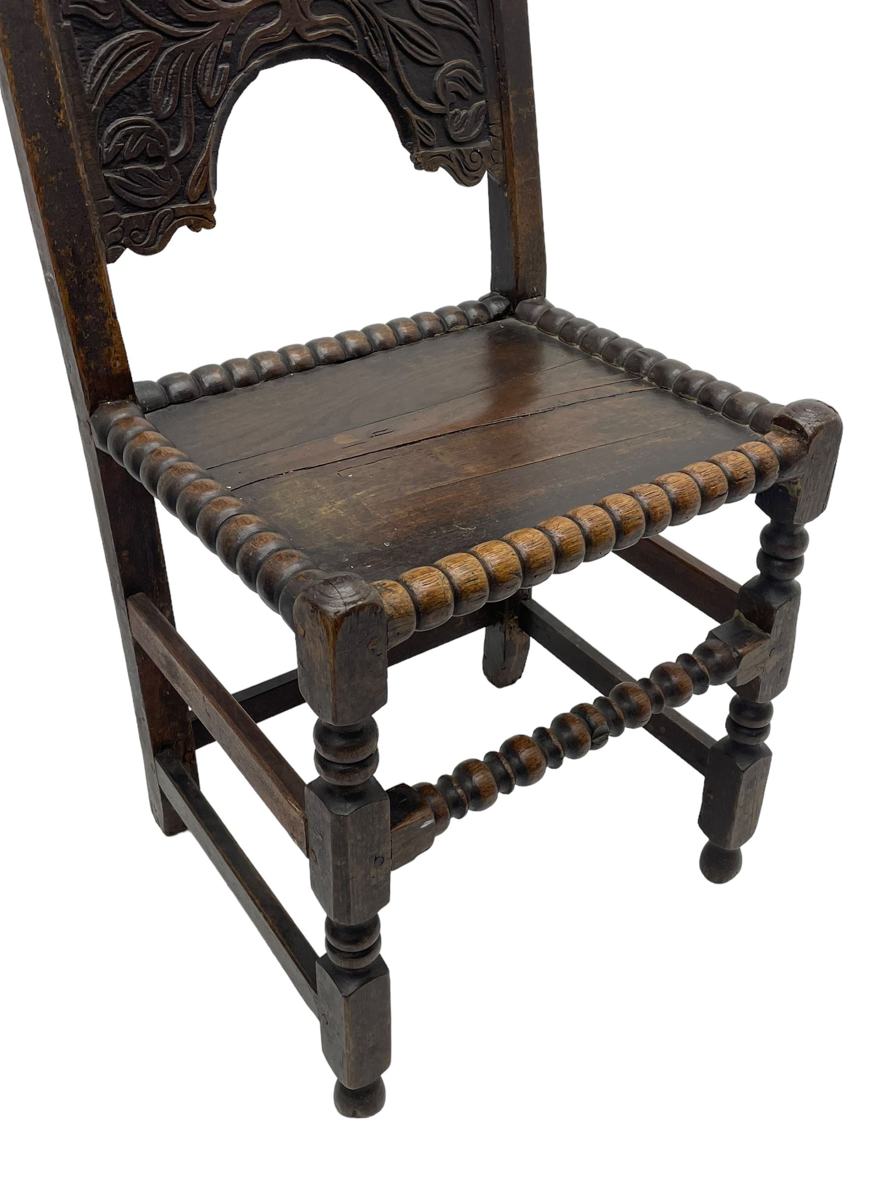 Set of three 18th century carved oak back stools, the cresting rail carved with scrolling foliate motifs over an arched panel with a stylised tree carving with extending leafage, the panelled seat held within a bobbin-turned frame, raised on turned supports united by a ring-turned front stretcher