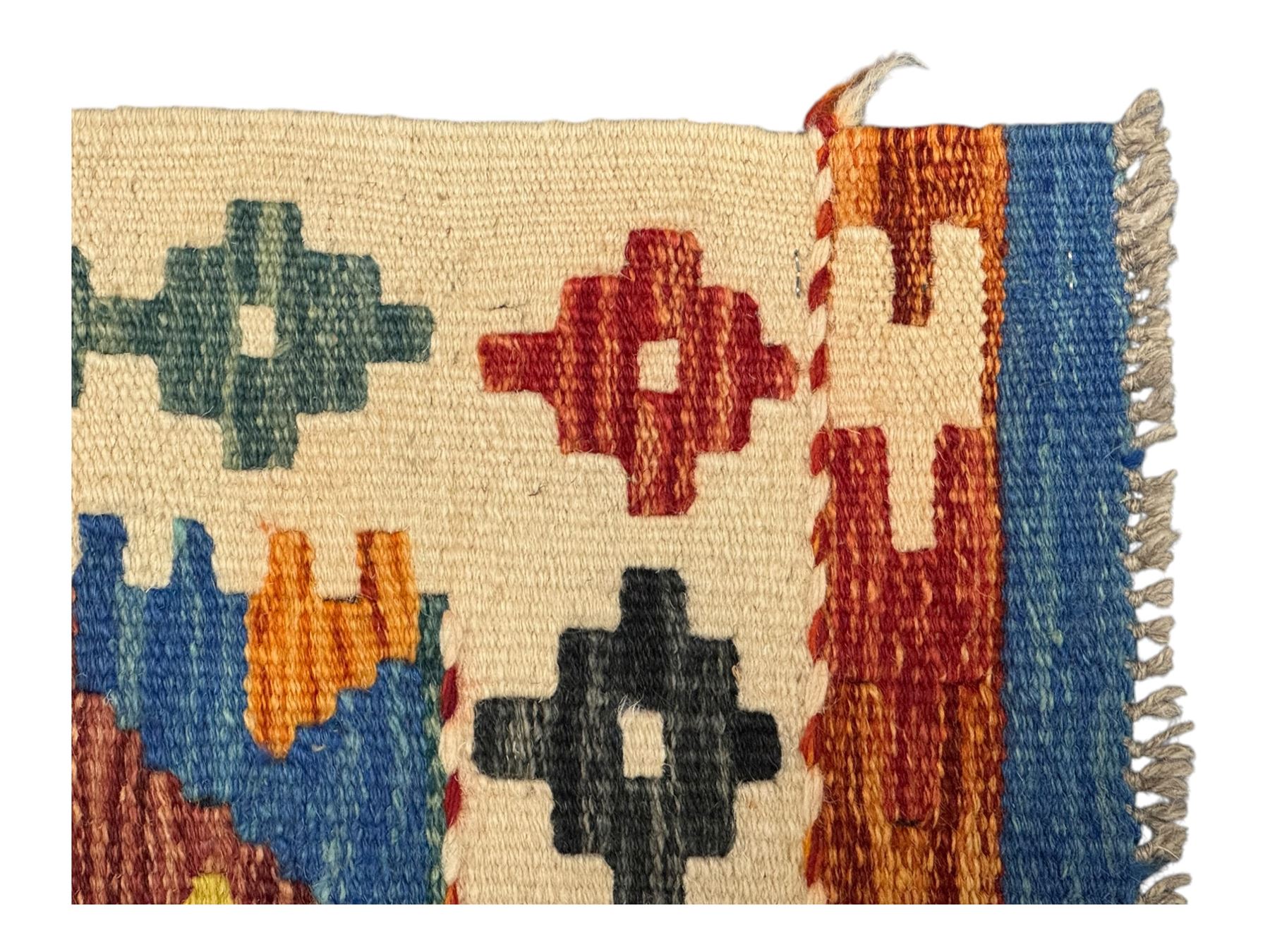 Kilim runner rug, central field decorated with four stacked geometric medallions in a multicoloured zigzag design, bordered by a series of small geometric motifs, fringed edges at both ends