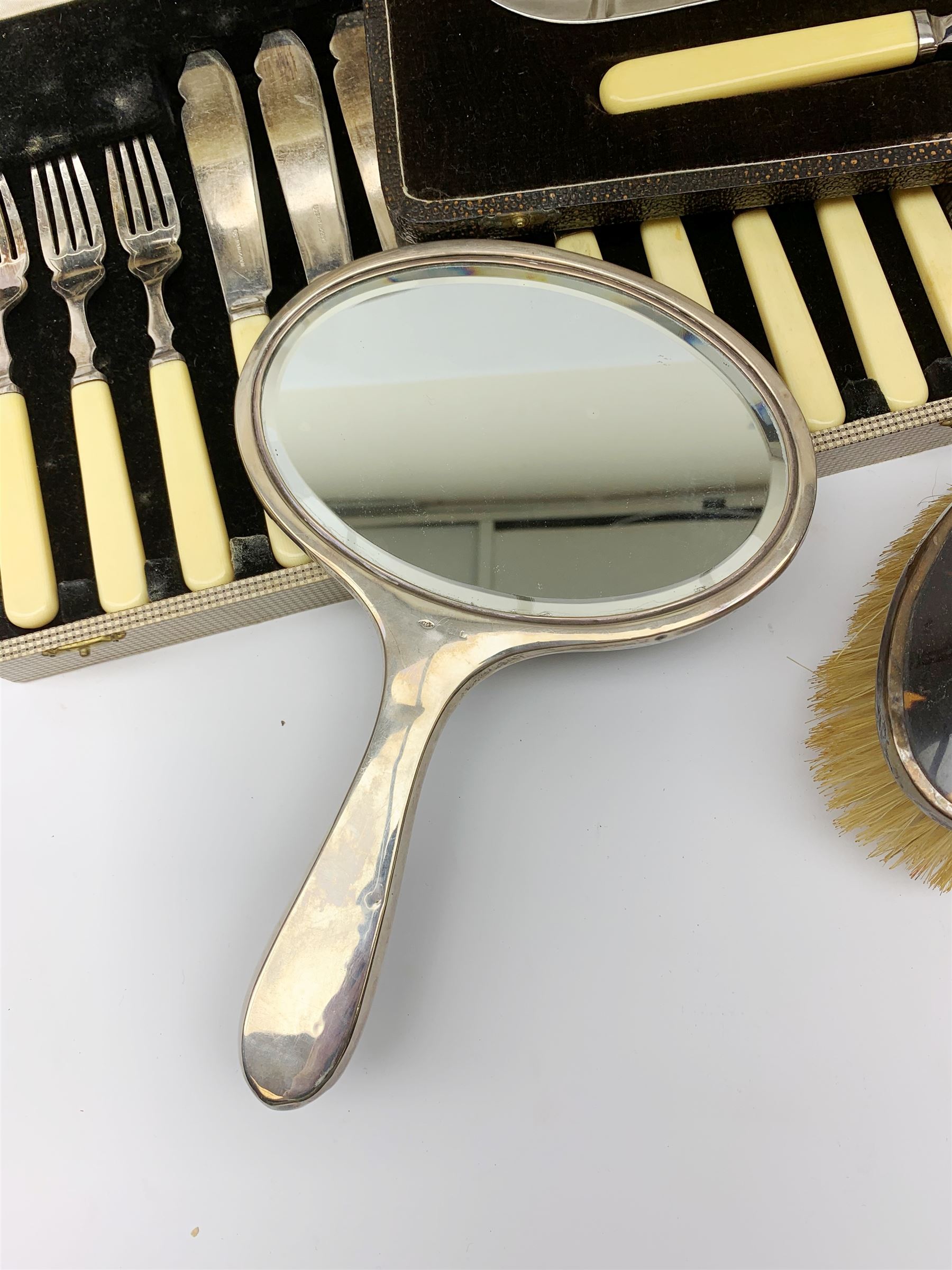 A silver mounted faux tortoiseshell dressing table set, comprising hand held mirror, two hair brushes, and two clothes brushes, each with inlaid swag to the back, hallmarked Lionel Smith & Co, Birmingham 1927, plus a silver mounted clothes brush with engine turned decoration and monogramed plaque, hallmarked William Neale & Son Ltd, Birmingham 1929, pair of silver plate on copper bottle coasters, cased set of fish servers, and cased set of fish eaters and servers, the knife blades marked Mappin & Webb. 