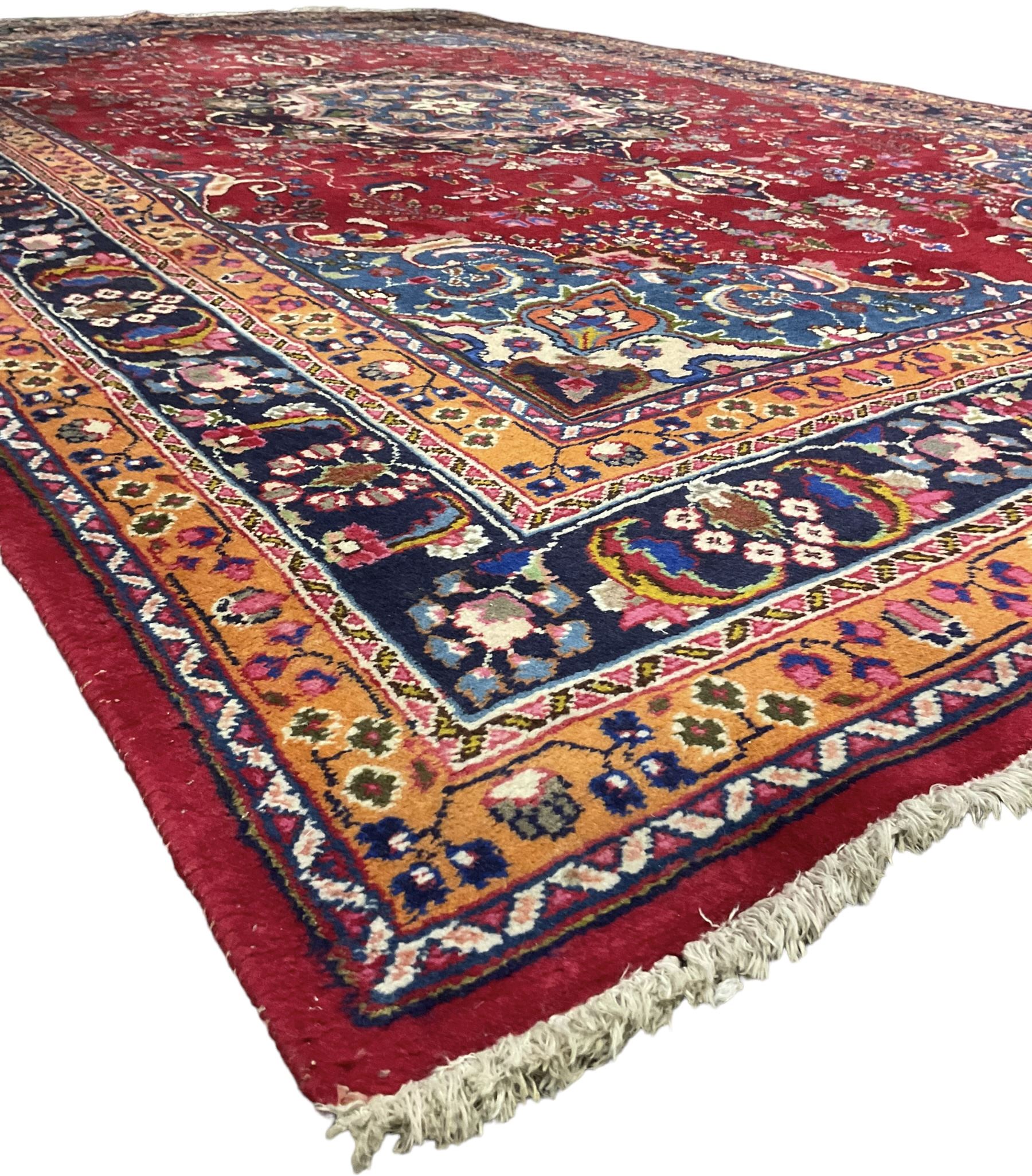 Persian Meshed red ground rug, central floral rosette medallion surrounded by trailing branch and stylised flower heads, repeating scrolling border