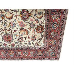 Persian Sarough ivory ground rug, the field decorated with curled leafy branches and palmettes, crimson ground border decorated with further palmettes and floral sprays, within guard stripes 