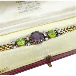 Early 20th century 15ct gold garnet, peridot and diamond, fancy link chain bracelet, the central cushion cut rhodolite garnet of approx 5.05 carat, with two cushion cut peridots set either side, spaced by three old cut diamonds, total diamond weight approx 0.35 carat, in fitted case by Garrard & Co