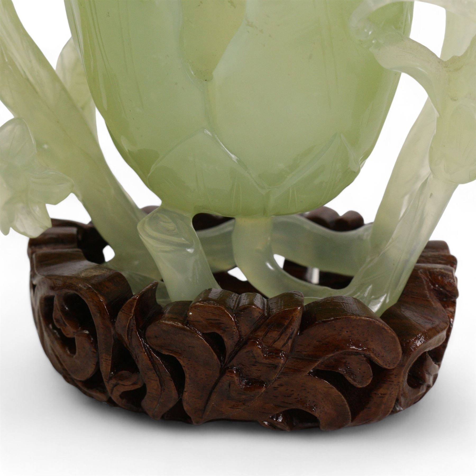 Chinese green jade magnolia form vase, supported on a leafy stem, with flowers and butterflies, on a pierced and carved hardwood stand, H15cm x W14cm