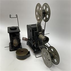 Early 20th century tinplate combined magic lantern and 35mm cinematograph projector, hand-cranked, with electric bayonet lamp, fitted with film reels, L35cm overall, and a similar projector by Gebruder Bing Nuremberg with spirit lamp (glass chimney a/f) L22cm, with two reels of film 