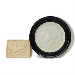 Plaster roundel of a warrior fighting a dragon, in an black frame, together with another p...