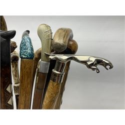 Oak barley twist stick stand, with a collection of walking sticks including examples with carved pommels, horn handles, silver collar etc, together with brass stick stand 