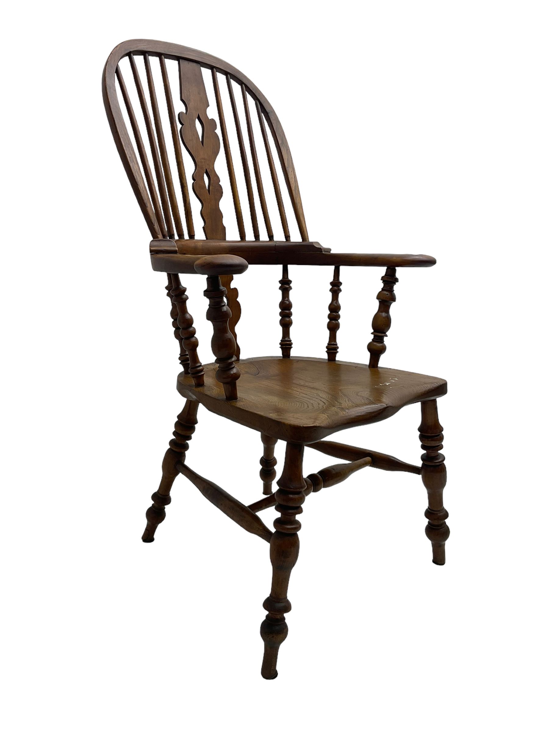 Elm and beech high back Windsor chair,  high hoop back with pierced splat and spindle supports over shaped saddle seat, raised on ring turned supports united by H-stretcher