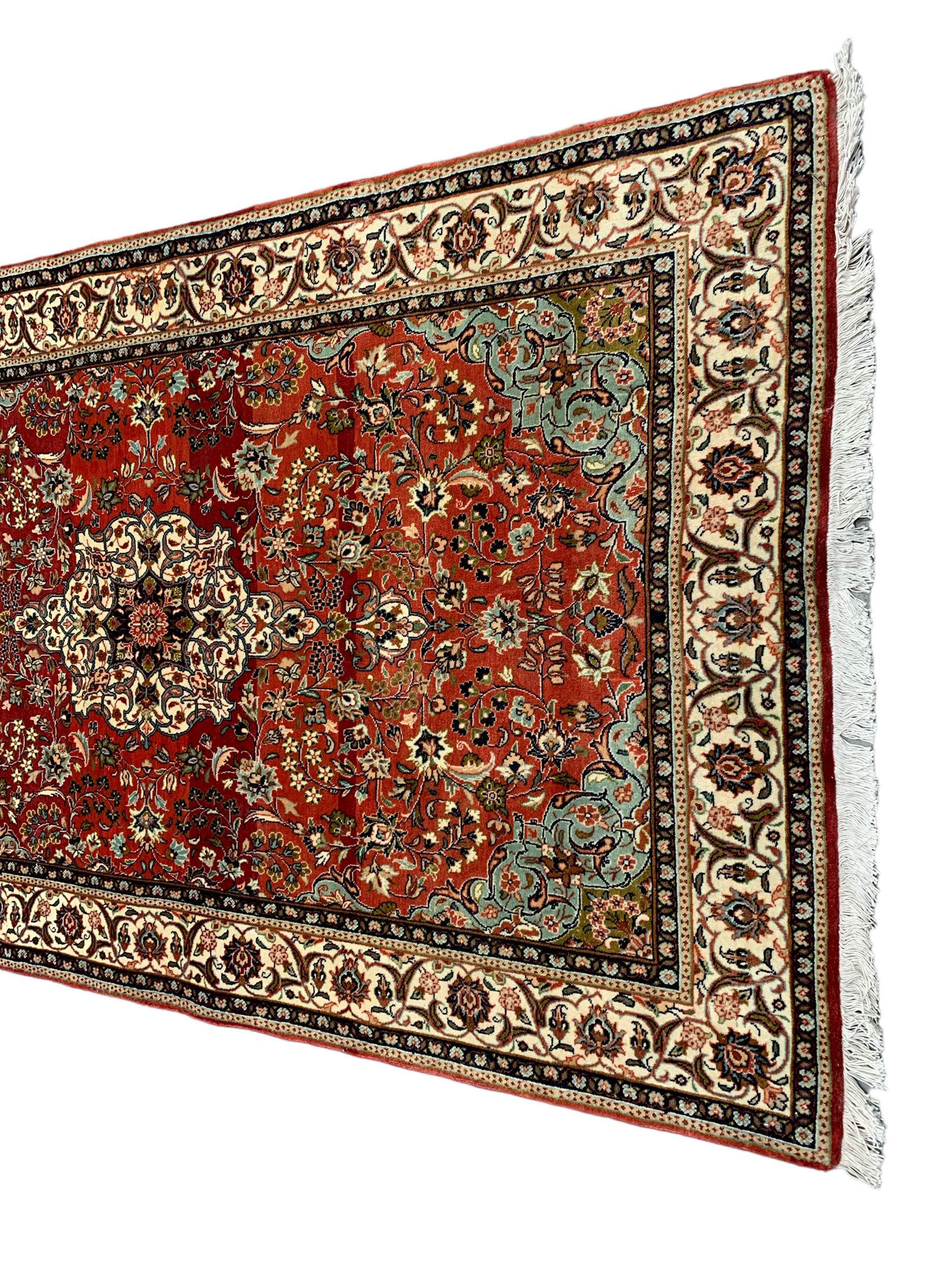 Small Persian Kashan crimson ground rug, the central interlaced medallion surrounded by scrolling foliate branches and stylised plant motifs, scrolling border with guard bands