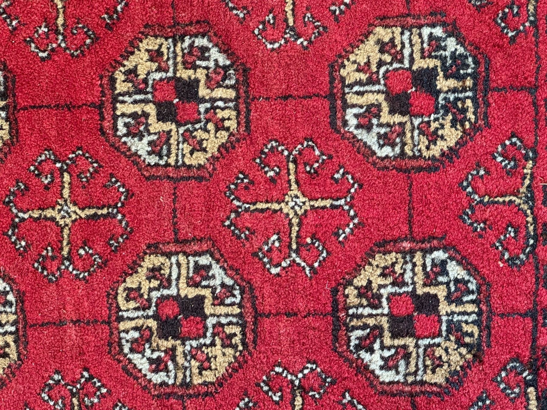 Afghan red ground Bokhara rug, decorated with four central Gul motifs, enclosed by wide geometric guard bands (191cm x 104cm); together with another similar (120cm x 79cm)