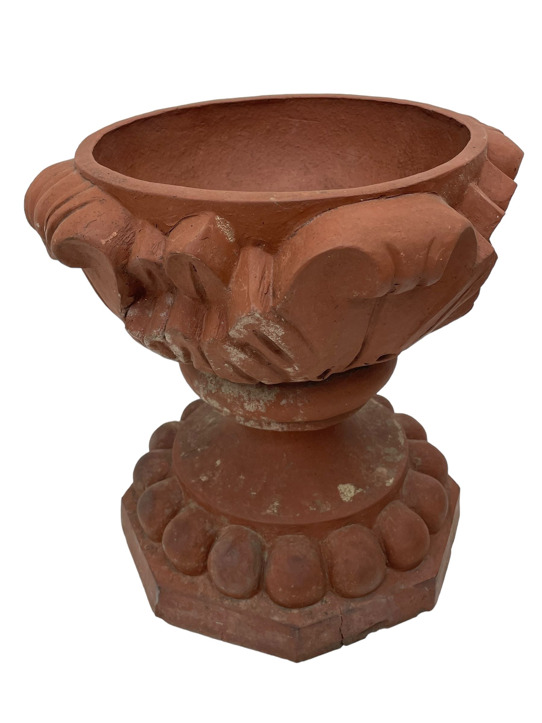 Pair of late 19th to early 20th century red terracotta garden urn planters, the shallow bowls moulded with curled acanthus leaf decoration, on circular foot with globular beaded moulding, octagonal base