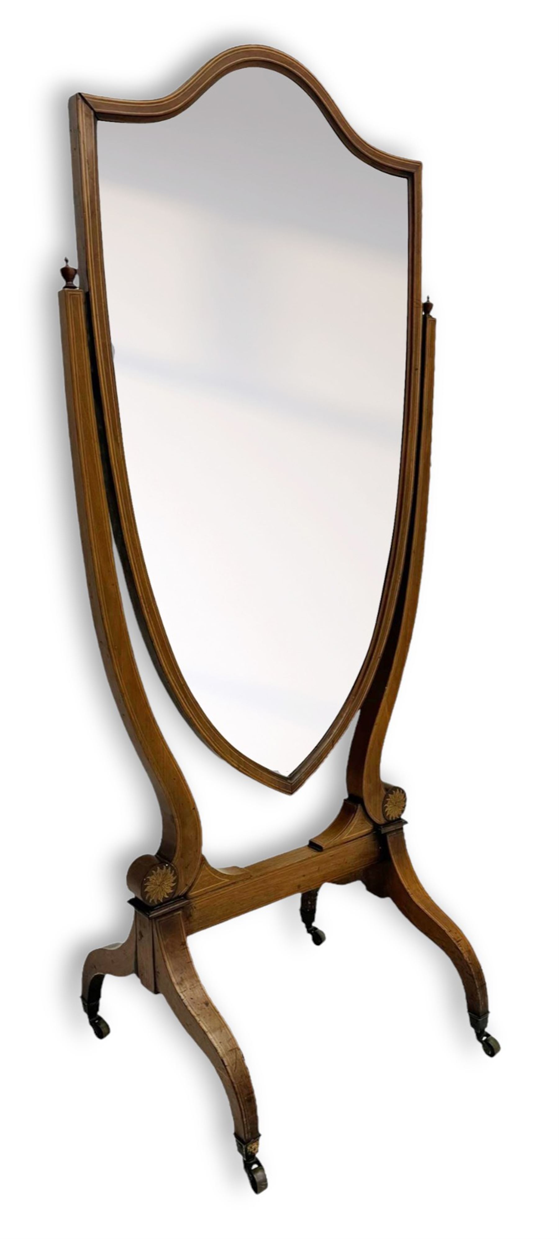 S. & H. Jewell - Edwardian mahogany cheval dressing mirror, shield shaped bevel edged mirror plate within an inlaid mahogany frame, supported by a pair of curved uprights topped with finials and terminating in a scroll design with floral inlay, the reverse bearing makers plaque, standing on four shaped supports fitted with brass castors