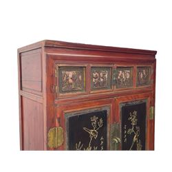 Late 19th century Chinese Qing dynasty red and black lacquered wood cabinet, Fujianese province, upper cupboard enclosed by two doors with relief carved and gilt panels depicting figures behind glass, the large cupboard enclosed by two panelled doors carved with trailing foliate branches and birds, inscribed with Chinese characters, to the left ‘Prolong life’ and to the right ‘Wealth and good fortune’, fitted with two drawers, square supports with carved brackets 