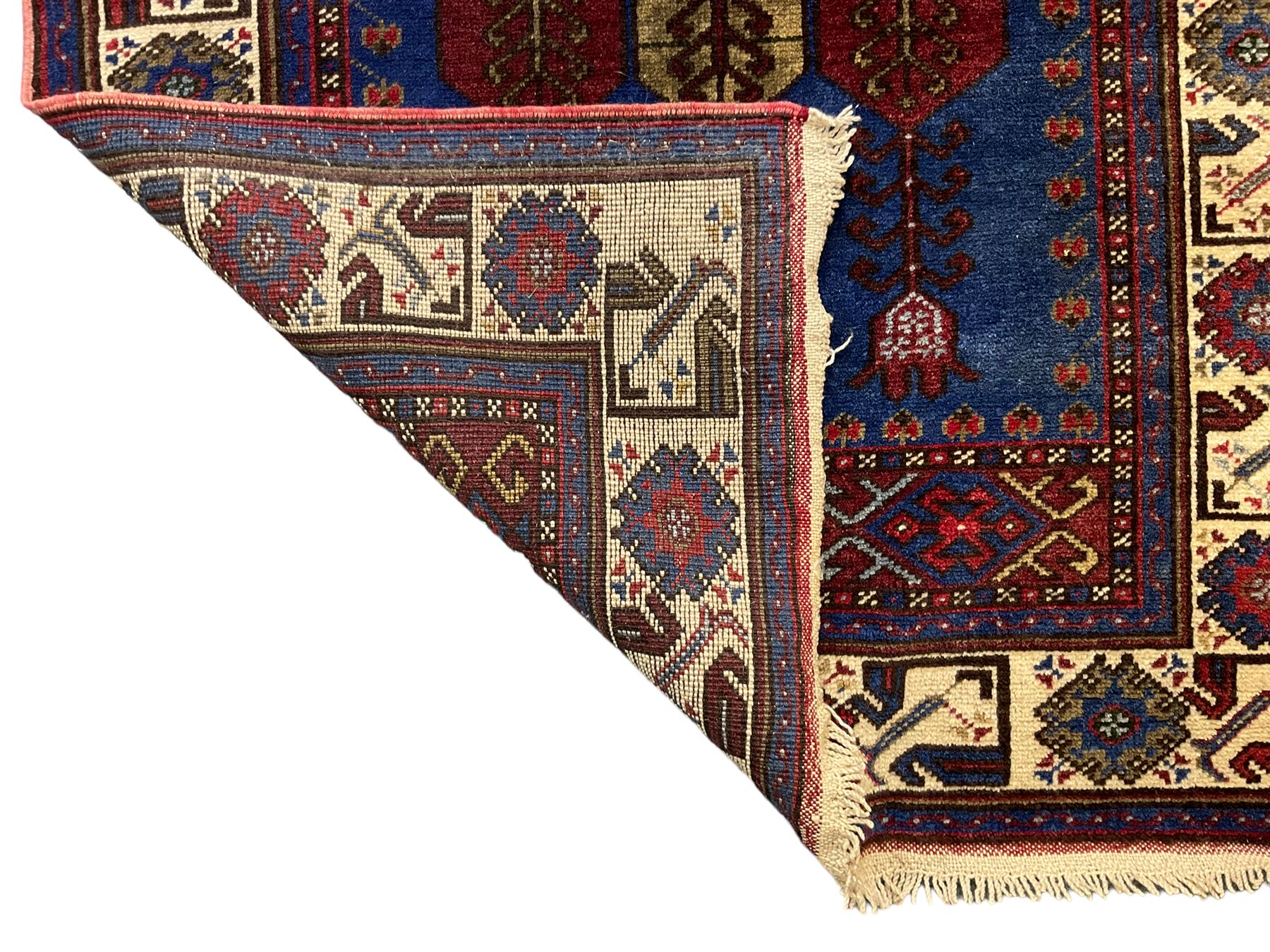 Turkish Yuruk indigo ground rug, the field decorated with geometric architectural designs, the guarded ivory border with repeating stylised plant motifs