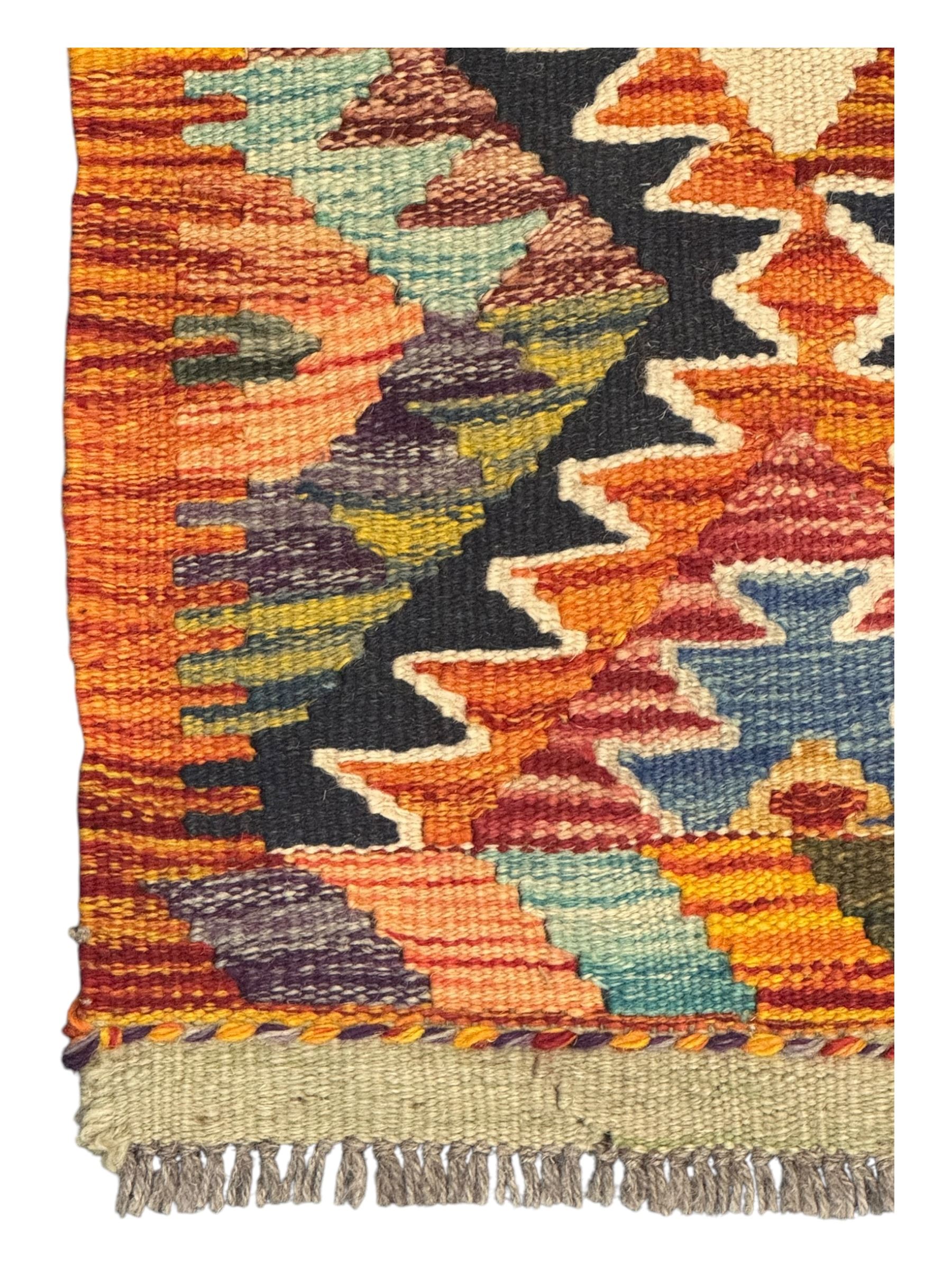 Chobi Kilim multicoloured ground runner, displaying diamond-shaped motifs in shades of blue, red, yellow, and green, accented by a bold black outline and bordered with a striped design, flatwoven with fringed edges