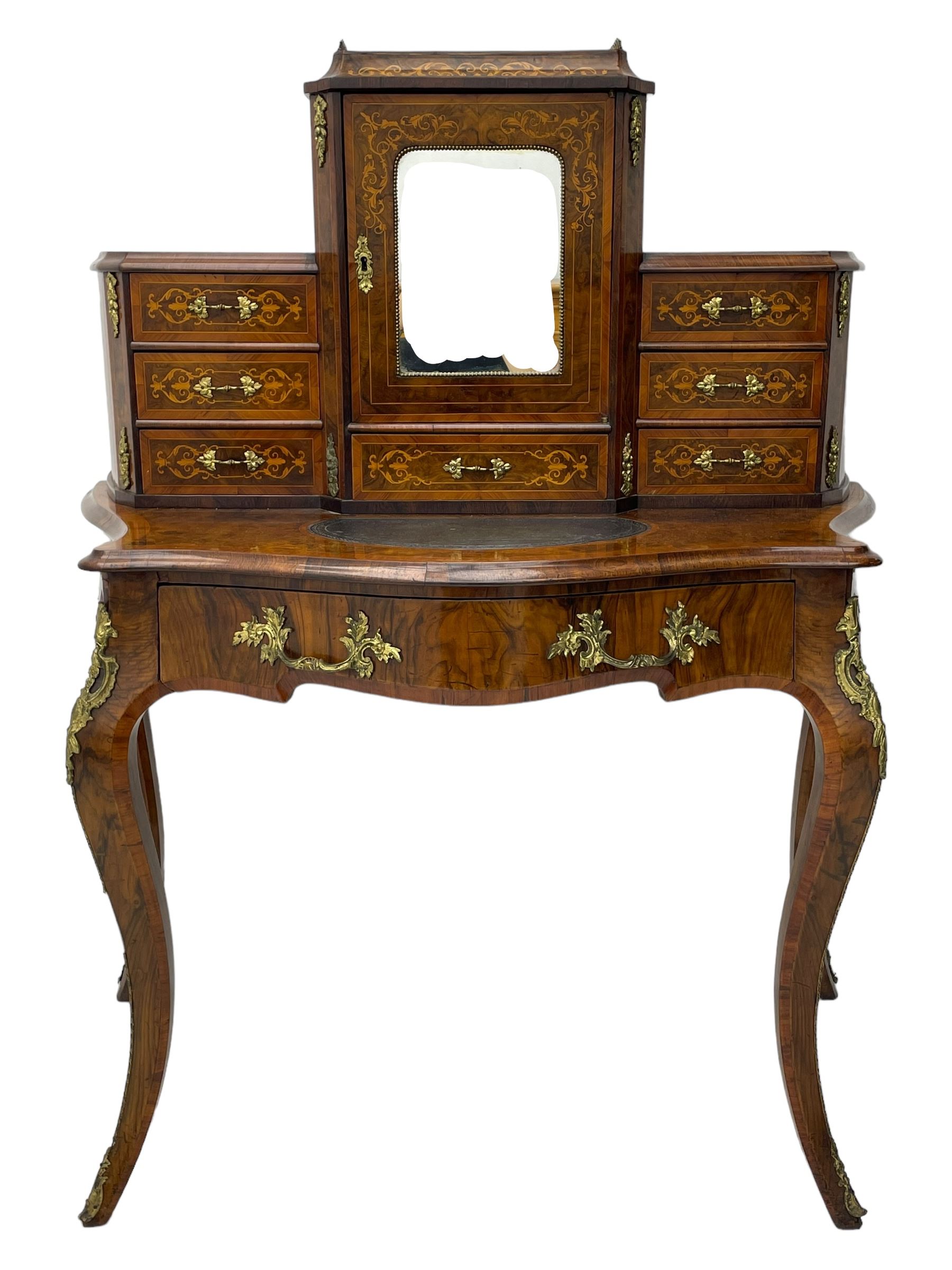 19th century French figured walnut Bonheur de Jour or writing desk, the upper section with brass gallery over mirror glazed cupboard and a combination of drawers, shaped and moulded top with leather inset and satinwood band, fitted with single drawer, on cabriole supports, inlaid throughout with scrolling foliate decoration in boxwood, ornate cast brass mounts 