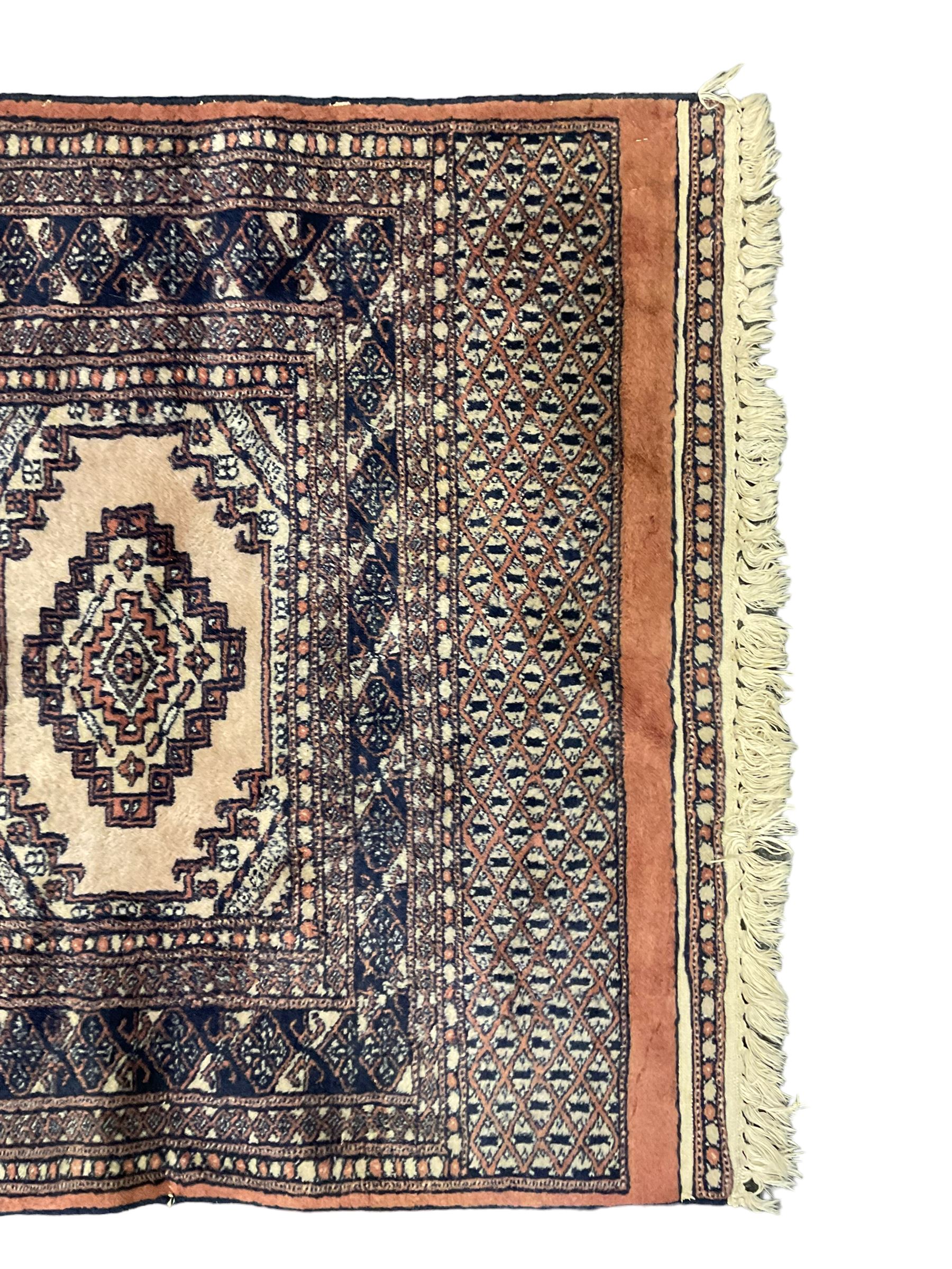 Persian peach ground rug, the field divided into four panels each with geometric lozenge, multiple band border with stylised flower head motifs, the end panels decorated with repeating lozenges